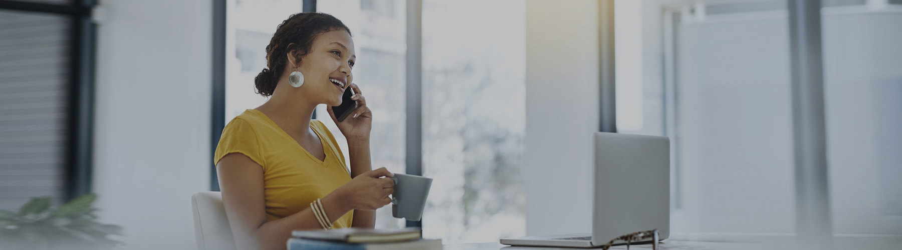 Woman on phone sitting at desk with coffee